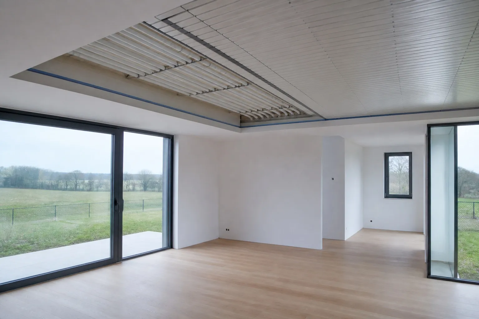 Klimaatplafond in opbouw met witte panelen en leidingen