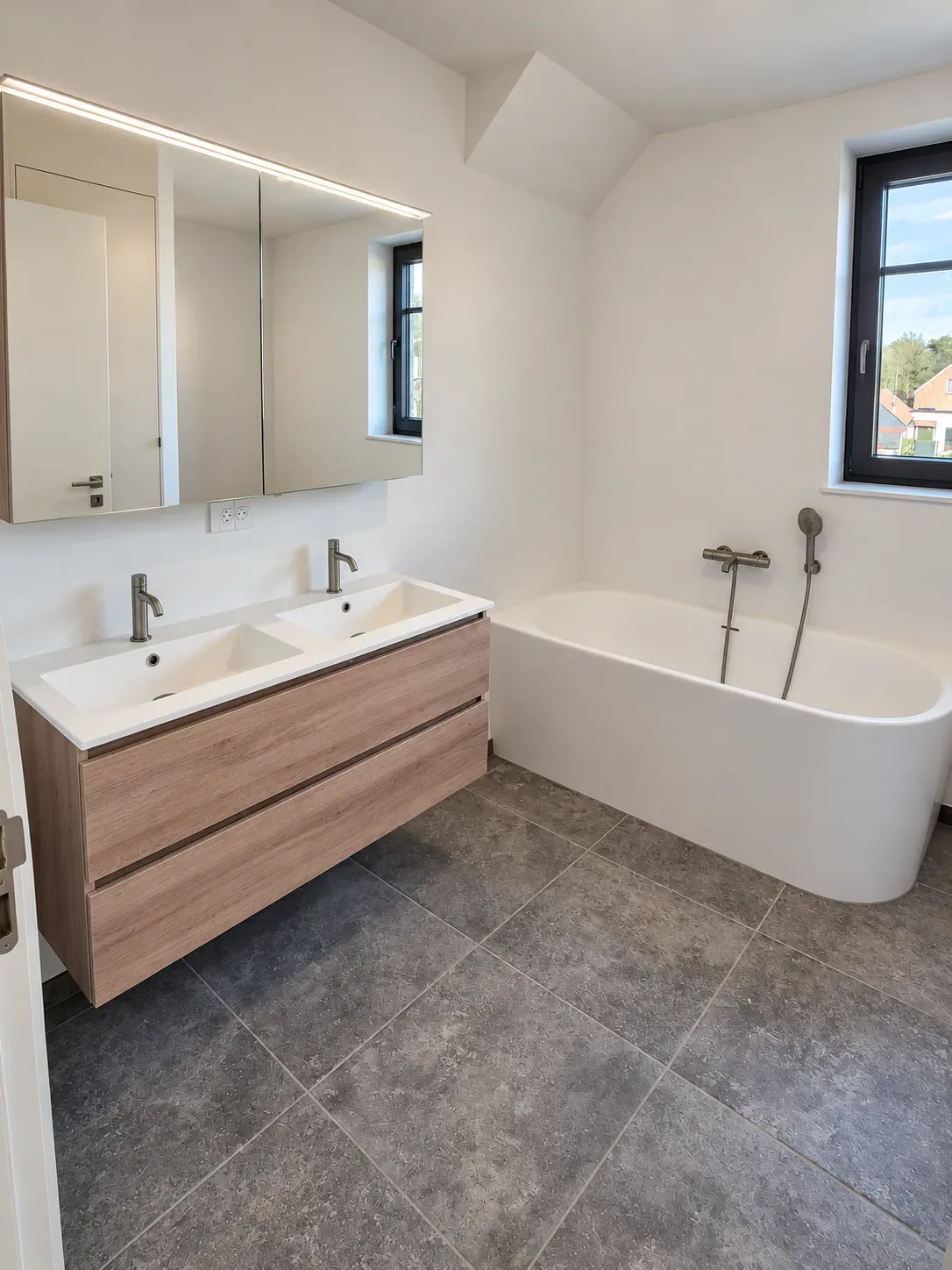 Badkamer met dubbele wastafel in eikenmeubel, vrijstaand bad en grijze natuursteenvloer